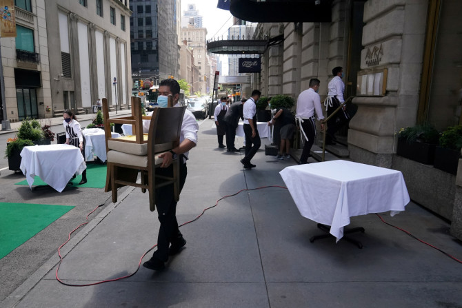 Un serveur installe des tables devant un restaurant dans une rue le premier jour de la phase deux de la réouverture des entreprises suite à l&#39;épidémie de la maladie à coronavirus (COVID-19), dans le quartier de Manhattan à New York