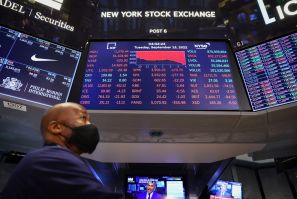 Un commerçant se tient sous un écran sur le parquet affichant le Dow Jones Industrial Average à la Bourse de New York (NYSE) à Manhattan, New York City