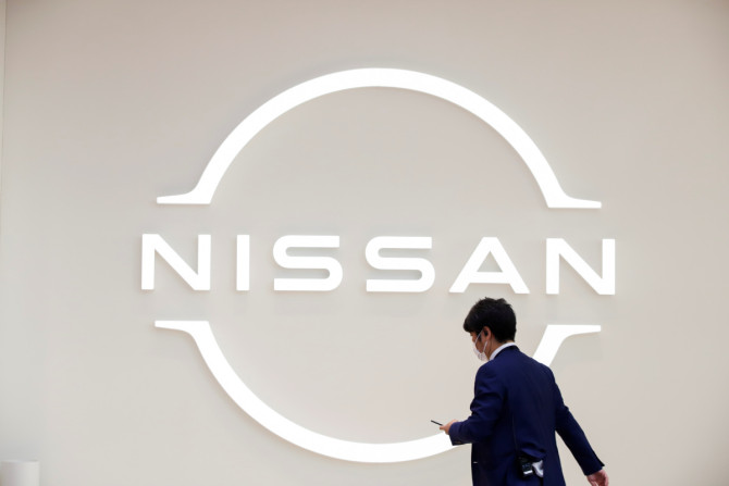 Un homme marche devant le logo Nissan à la Nissan Gallery de Yokohama