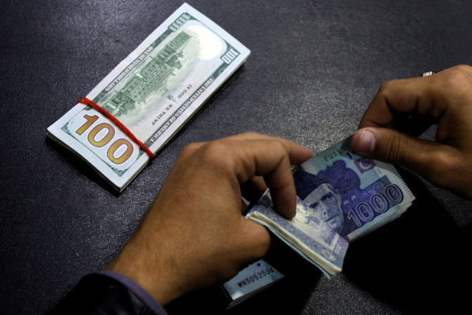 Un cambiste compte les billets en roupie pakistanaise alors qu&#39;il prépare un échange de dollars américains à Islamabad