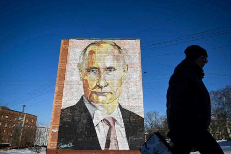 Une femme passe devant une peinture murale du président russe Vladimir Poutine sur un immeuble résidentiel de la ville de Kashira, au sud de Moscou