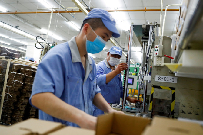 Des employés portant des masques travaillent dans une usine du fabricant de composants SMC lors d&#39;une visite organisée par le gouvernement de ses installations à la suite de l&#39;épidémie de la maladie à coronavirus (COVID-19), à Pékin