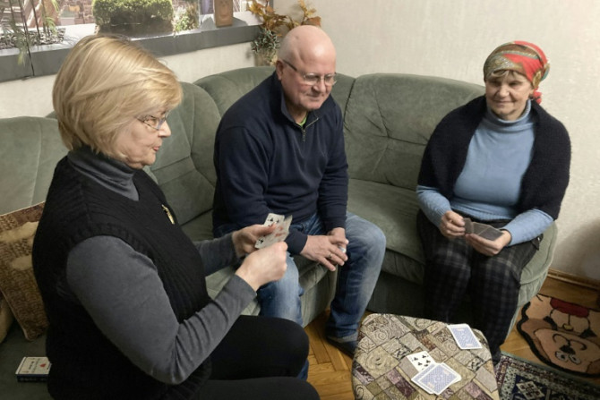 Raissa Ulinichi (L) joue aux cartes avec les réfugiés ukrainiens Viktor Klopotovsky et sa femme Maria Klopotovsky qu&#39;elle a accueillie chez elle