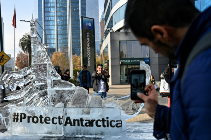 Des passants prennent des photos d&#39;une sculpture de glace représentant un krill à Santiago le 19 juin 2023 alors que la Commission pour la conservation de la faune et de la flore marines de l&#39;Antarctique s&#39;est réunie pour discuter de trois nou