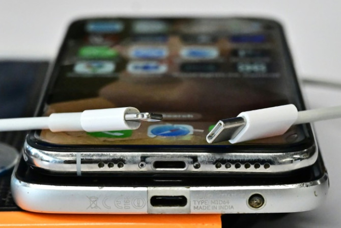 Un chargeur USB-C (R) et un chargeur Apple Lightning traditionnel (L) sont visibles sur un Apple iPhone