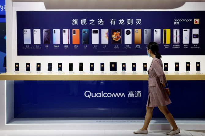 Une femme passe devant un comptoir affichant des téléphones portables sur le stand Qualcomm lors du Salon international chinois du commerce des services (CIFTIS) 2021 à Pékin, en Chine, le 4 septembre 2021.