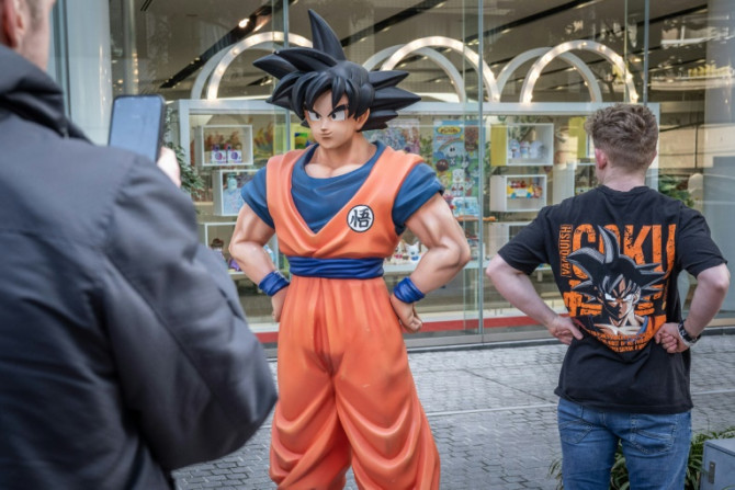 Un touriste portant un T-shirt de Dragon Ball se fait prendre en photo avec une statue du personnage de Dragon Ball "Son Goku" à Tokyo