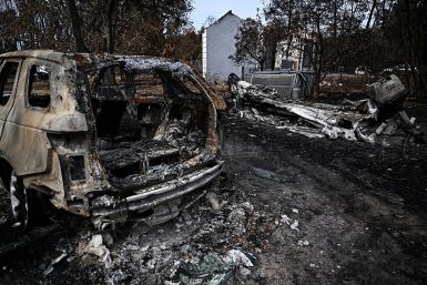 This photograph shows a burnt car and a burnt boat