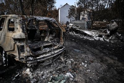 This photograph shows a burnt car and a burnt boat